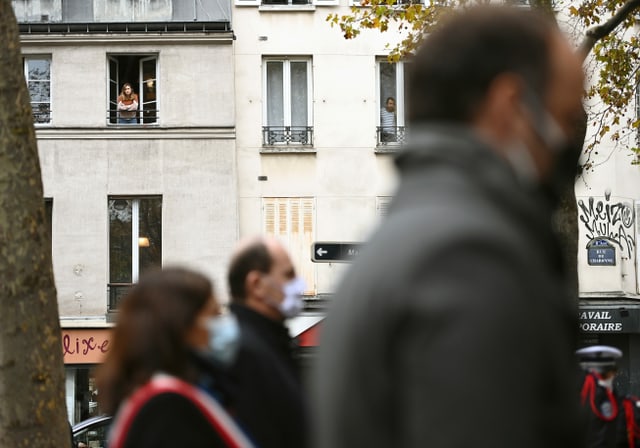 Menschen beobachten die Gedenkzeremonie mit Premierminister Jean Castex und Bürgermeisterin Anne Hidalgo aus dem Fenster heraus. 