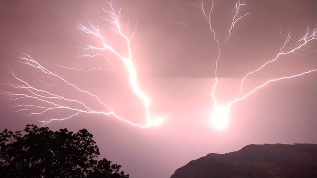 Blitz, der von Bergspitze in den Himmel geht.