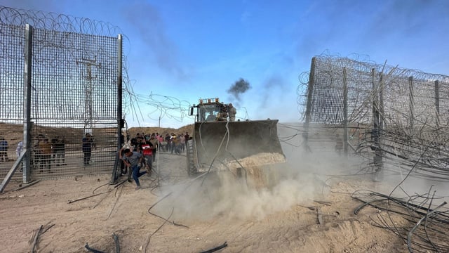 Bagger zerstört Grenzzaun. 