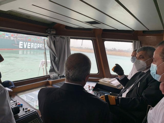 Mitglieder der Suezkanal-Behörden begutachten die Havarie und besprechen das weitere Vorgehen. Das Containerschiff soll mit mehreren Schleppern wieder ins richtige Fahrwasser gezogen werden.