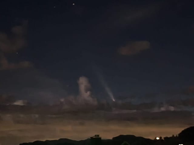 Nachthimmel mit Komet über Wolken.