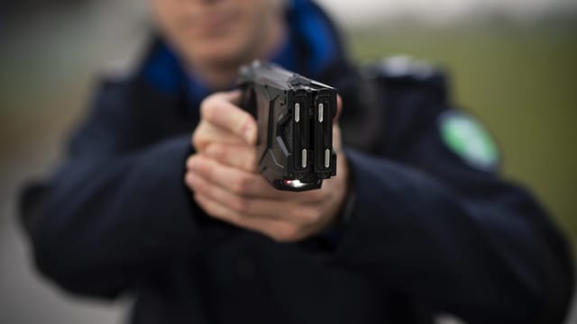 Ein Polizist richtet einen Taser auf sein Gegenüber.