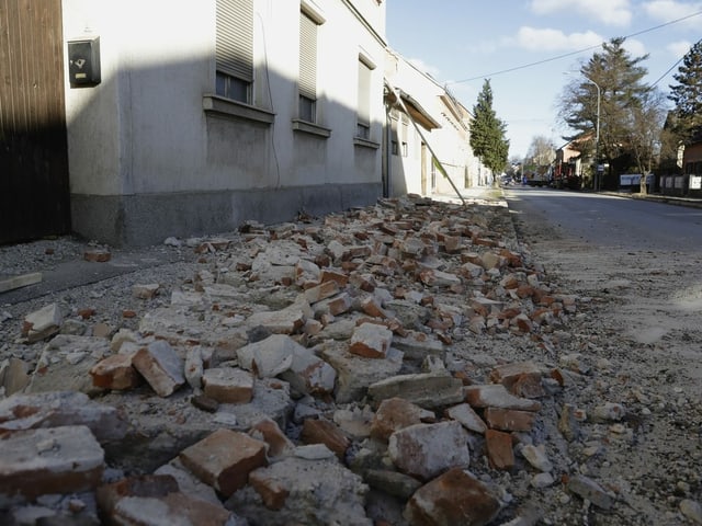 Debris covers the street in front of a row of houses.