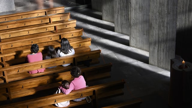 Kirchenbänke mit ein paar wenigen Personen, die darin sitzen