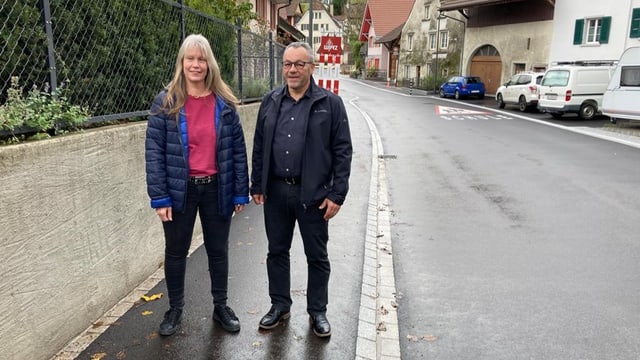 Eine Frau und eine Mann stehen auf dem Trottoir.