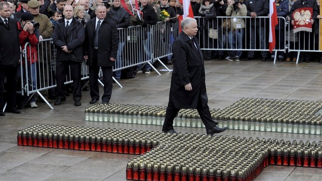 Jaroslaw Kaczynski schreitet durch ein Kreuz aus Grabkerzen zum Gedenkort seines Bruders.