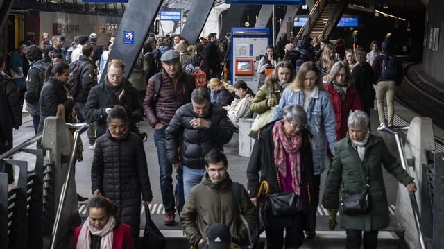 Menschen verlassen ein Perron, in dem sie eine Treppe hinuntersteigen.