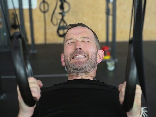 Mann verzieht sein Gesicht an einem Fitnessgerät.