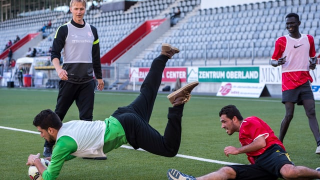 Flüchtlinge kämpfen im Training im Thuner Stadion um den Ball.