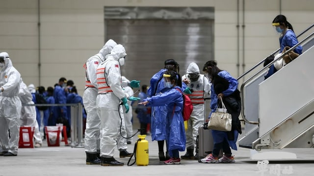 Am Flughafen führen Menschen in Schutzanzügen Coronatests bei Ankömmlingen durch.