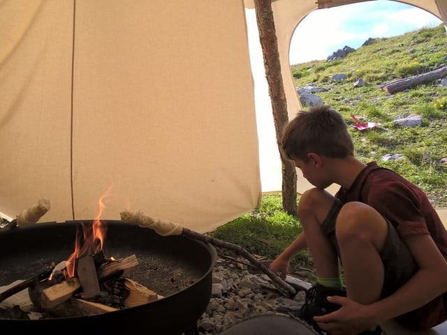 Kinder sitzen am Feuer im Tippizelt.