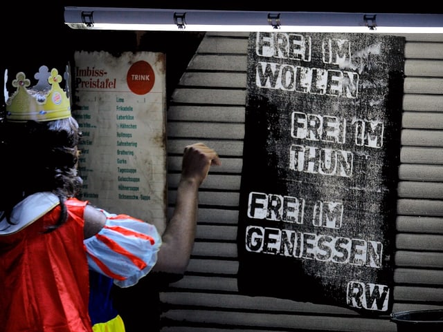 Eine als Schneewittchen verkleidete Person steht vor einem Plakat