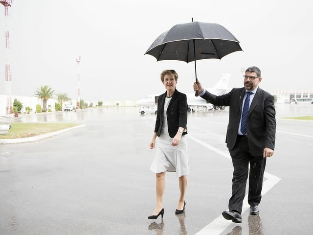 Simonetta Sommaruga bei Regen mit einem Schirm geschützt