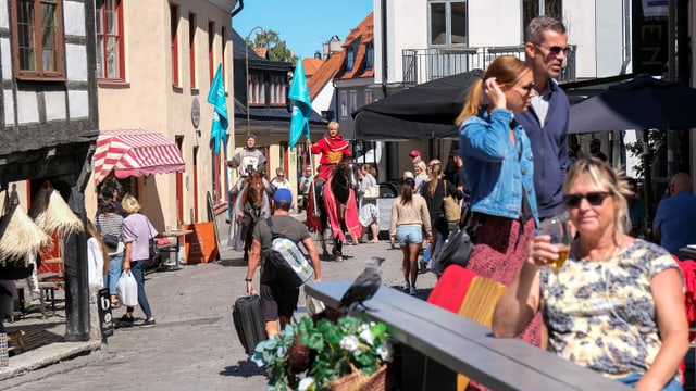 Touristen und zwei Ritter auf Pferden zwischen den historsichen Riegelhäusern in Visby/Gotland.