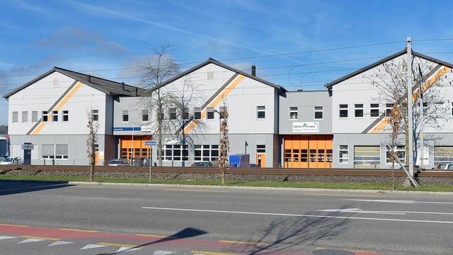 Drei neuere Häuser mit bunten Streifen, davor breite Strasse