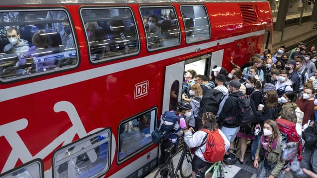 Viele Menschen steigen in einen deutschen Zug ein.