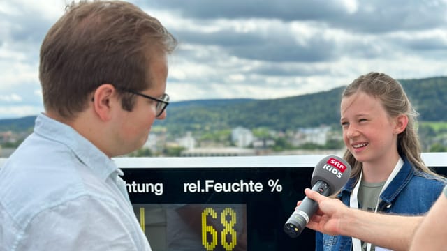 Kinderreporterin interviewt Simon Eschle auf dem Meteo-Dach über den Häusern von Zürich