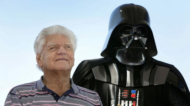 A man next to a Darth Vader figure.