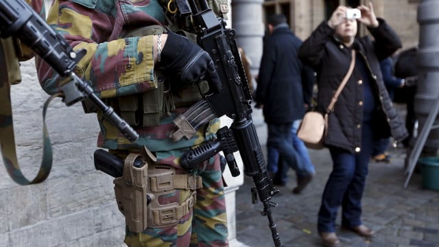 Soldaten mit Gewehr neben fotografierender Touristin