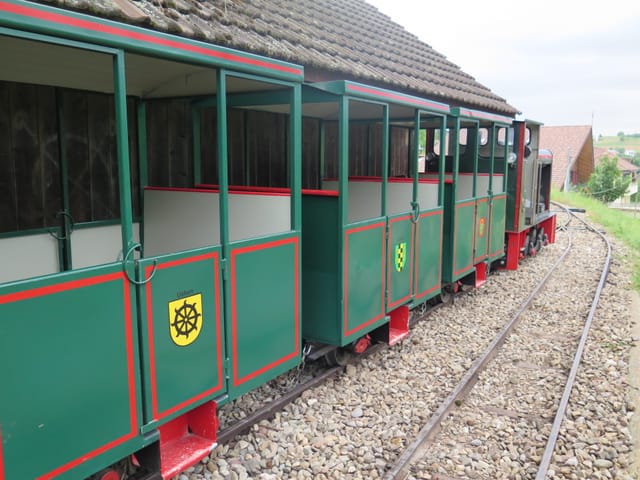 Grüne Eisenbahnwaggons, davor eine grüne Lokomotive.