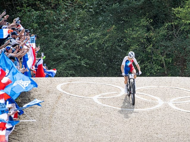 Radfahrer bei Olympischen Spielen, jubelnde Menge.