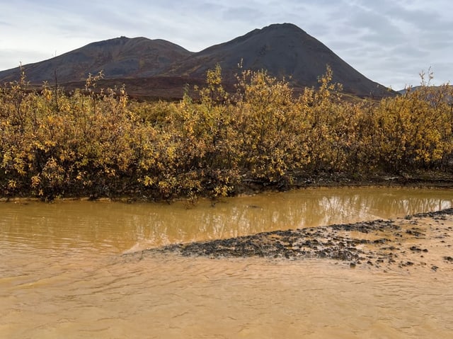 Ein Zufluss mit orange-Färbung in einer Landschaft.