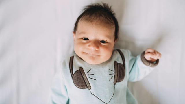 Symbolbild: Baby im Strampelanzug, es lächelt.