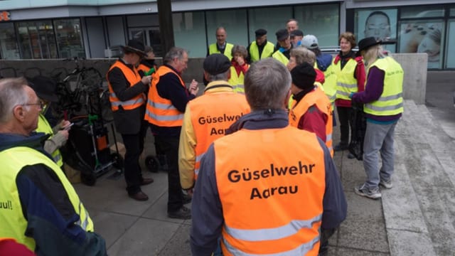 Leute in orangen Leuchtwesten mit Aufschrift "Güselwehr Aarau"