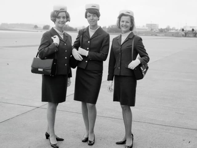 Schwarzweissfoto: Drei Frauen in Uniform mit knielangen Röcken und weissem Filzhut