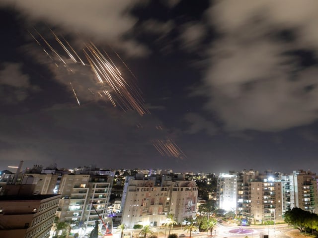 Raketenspuren am Nachthimmel über einer Stadt.