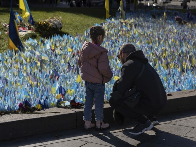 Ein Mann und seine Tochter besuchen das Denkmal für die im Krieg gegen Russland gefallenen ukrainischen Soldaten.