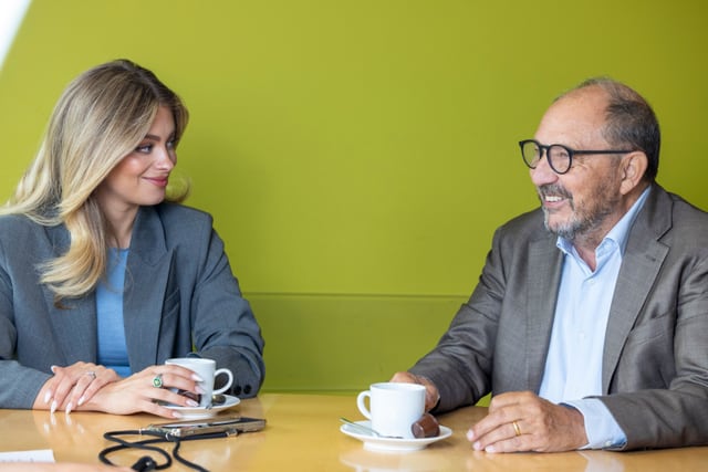 Jennifer Bosshard und Bernard Thurnheer sitzen am Tisch und diskutieren.