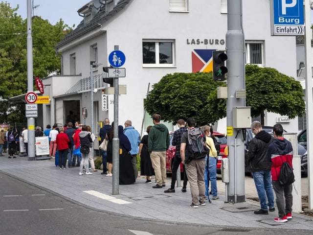 Leute stehen an und scheinen lange warten zu müssen.