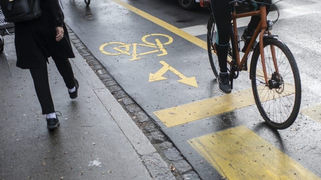 Velofahrer auf Veloroute neben Auto fahrend. 