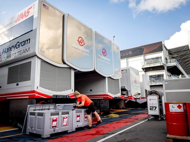 Person arbeitet vor Boxen in einem Formel-1-Fahrerlager.