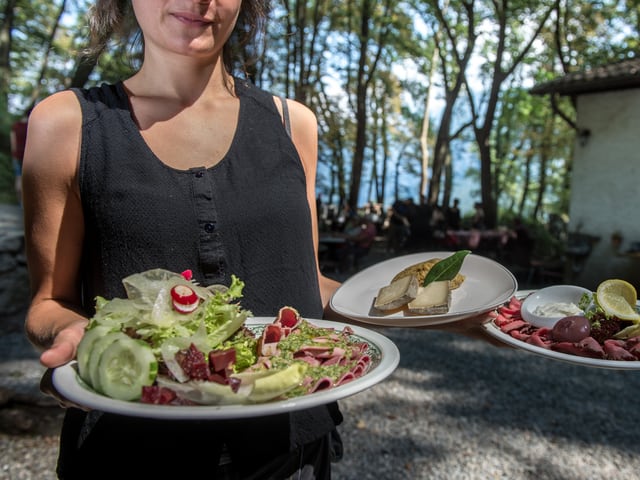 Frau bringt drei Teller mit Essen.