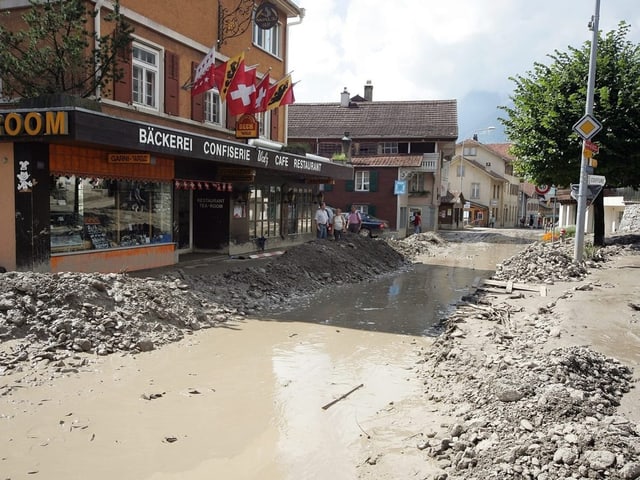 Das Dorfzentrum von Brienz. Die Strasse ist vom Schutt und Geröll befreit, nur noch dunkles Wasser deckt den Boden.