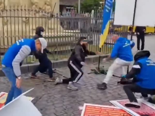 Menschen in blauen Westen heben Schilder auf einer gepflasterten Strasse auf.