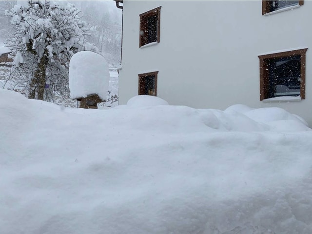 Mountains of snow in front of a wall of houses.