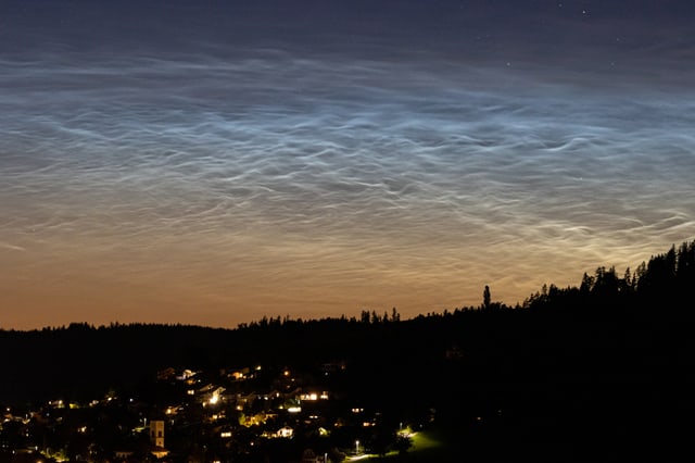 Silbern leuchtende Nachtwolken am dunklen Himmel.