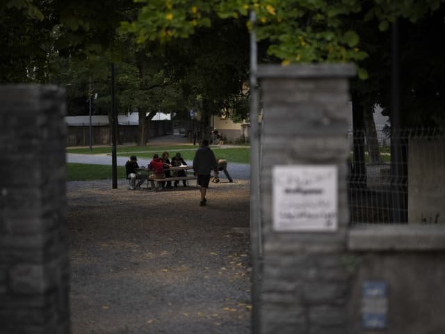 Menschen sitzen weit hinten an einem Tisch, vorne Gemäuer