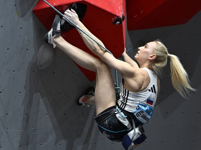 Frau klettert an einer Kletterwand in der Halle.