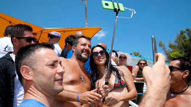 Matteo Salvini posiert mit Anhängern am Strand für ein Selfie.