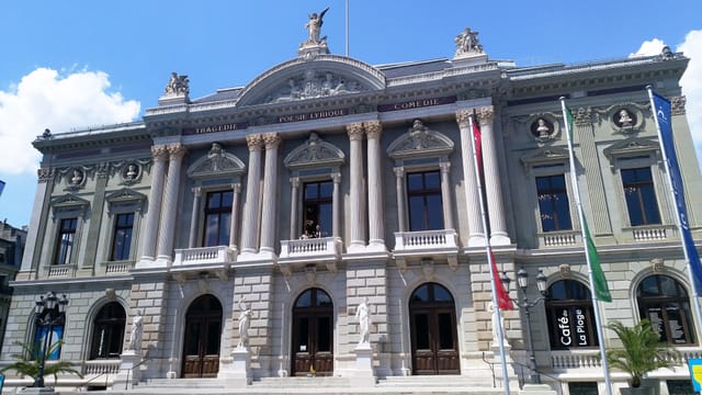 Ein grosses Konzertgebäude mit Statuen und Säulen und wehenden Fahnen. 