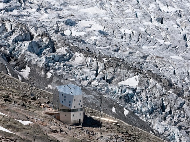 Eine SAC-Hütte vor einer Berglandschaft.