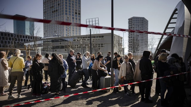 Menschen stehen mit Koffern in der Schlange