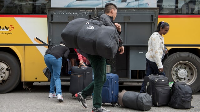 Flüchtilnge steigen in ein Postauto ein. 