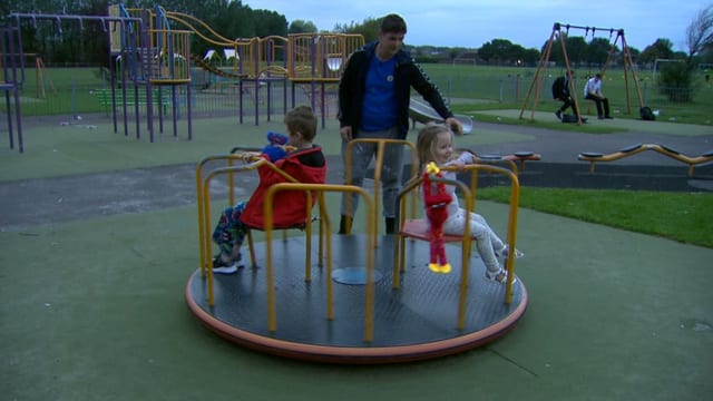 Der Vater spielt mit seinen Kindern auf dem Spielplatz.