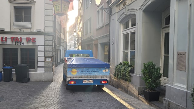 Ein Lieferwagen fährt durch eine schmale Gasse.