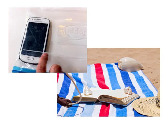 Handy in einem Gefrierbeutel und Badetuch am Strand.